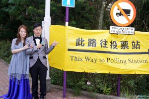 Au Nok-hin and his bride pose by a sign to a polling station for the New Territories East Legco by-election in February 2016 (from Au's Facebook page)